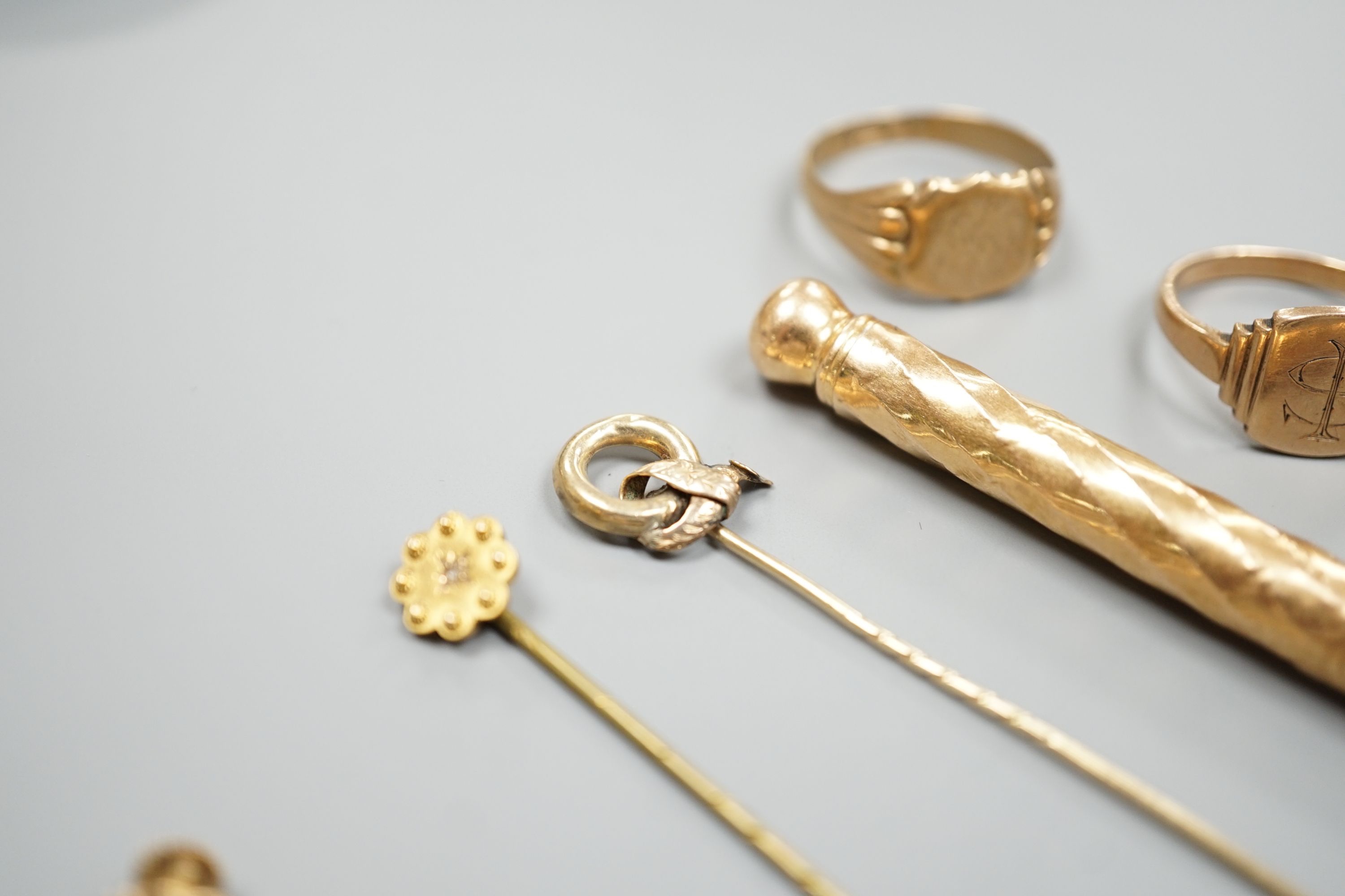 Four assorted 9ct rings including a Victorian buckle ring, 14 grams, two stick pins including part 15ct, a pair of yellow metal ear clips and a yellow metal overlaid propelling pencil.